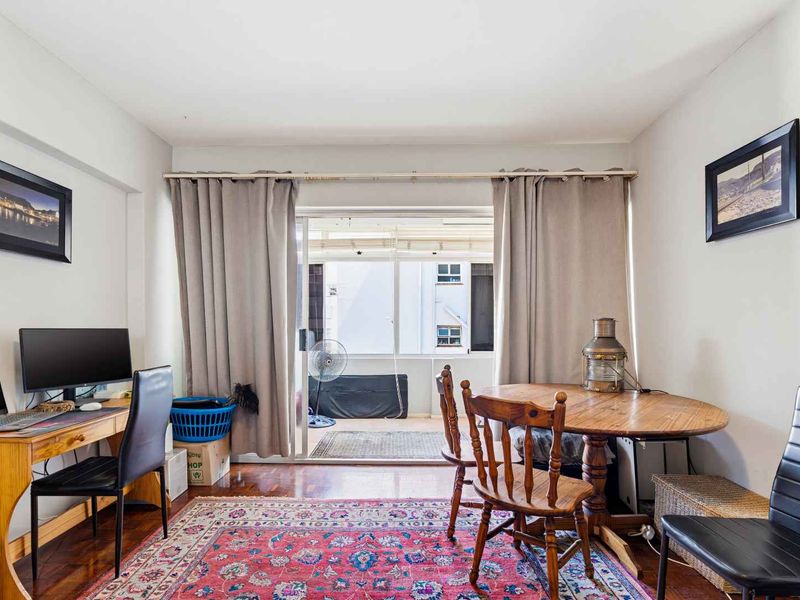 A bright living area featuring hardwood flooring and a large sliding glass door that opens onto a balcony, providing natural light.