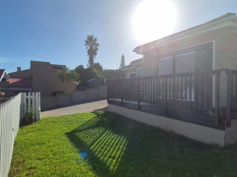 Rear view of the townhouse featuring a timber deck with balustrade, a white picket fence, and a paved driveway area.