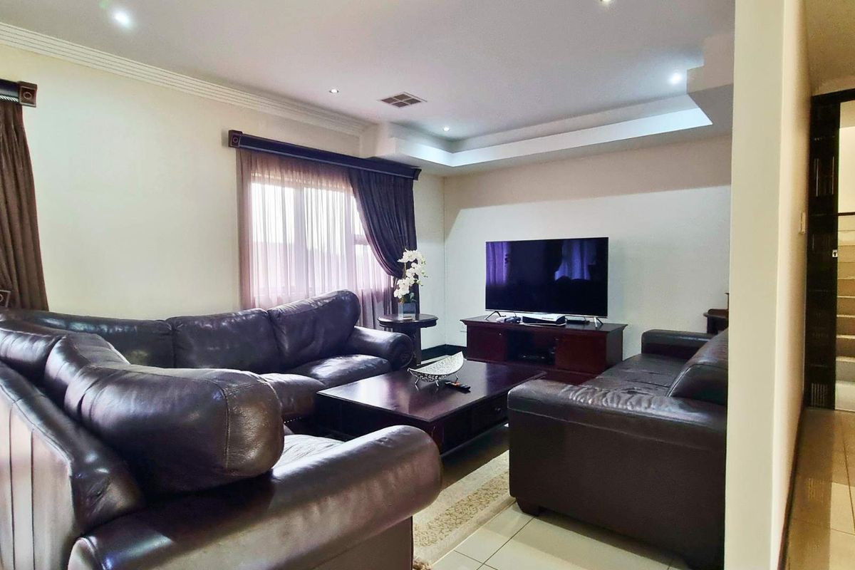 A comfortable living room featuring tiled flooring, recessed ceiling lighting, and a staircase leading to the upper level.