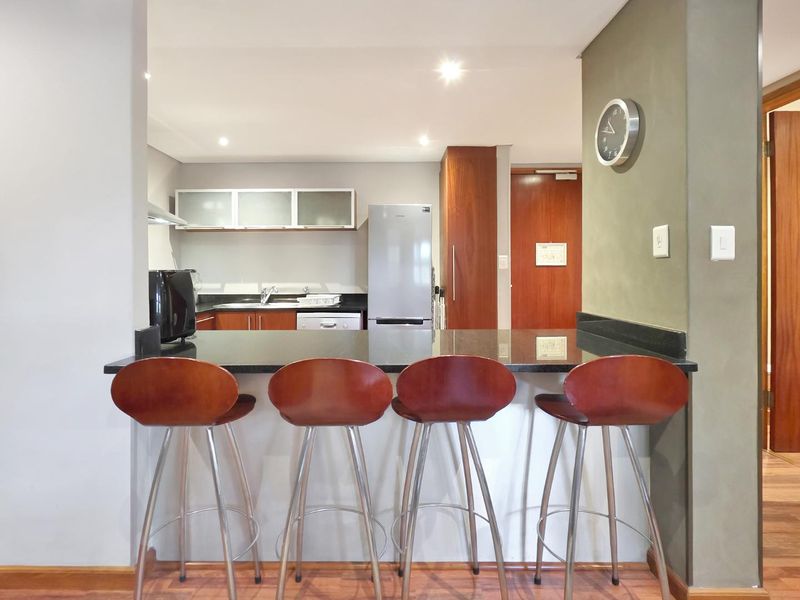 Open plan kitchen featuring a granite breakfast bar, built-in cabinetry, and modern recessed lighting, seamlessly integrated into the living space.