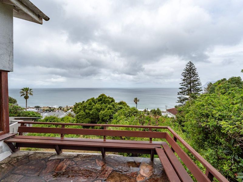 An elevated outdoor patio featuring stone paving and a built-in timber bench, offering expansive coastal and ocean views.
