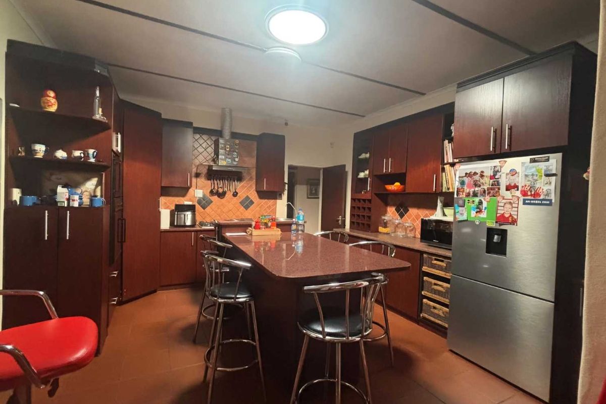 A functional kitchen featuring dark wood cabinetry, a central island with seating, tiled backsplash, and tiled flooring.