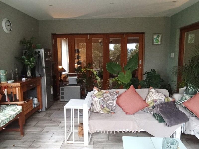 A comfortable living area featuring tiled flooring, recessed downlighting, and large timber folding doors that provide access to the outdoor space.