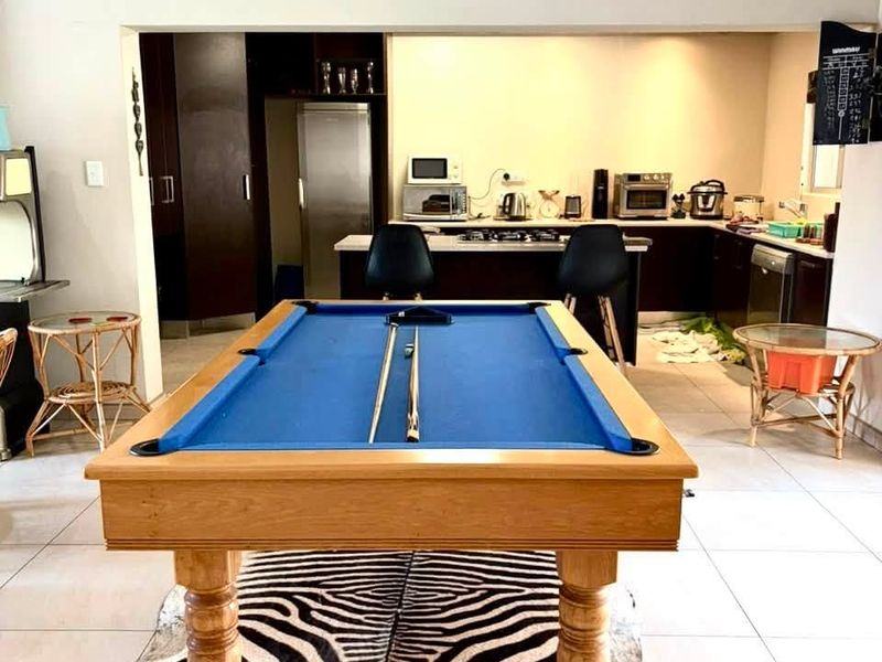 Open plan living area featuring a kitchen with dark cabinetry and a central island, seamlessly connected to a spacious entertainment zone.