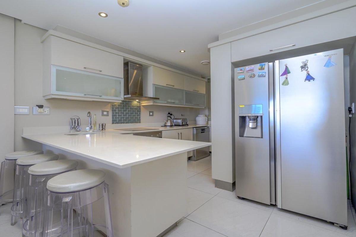Modern kitchen featuring sleek cabinetry, quartz countertops, a tiled backsplash, and integrated stainless steel appliances, offering a clean and functional culinary space.