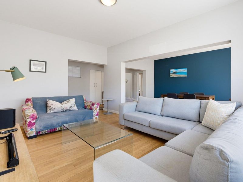 Spacious open-plan living and dining area featuring hardwood flooring, neutral walls, and a striking blue accent wall.