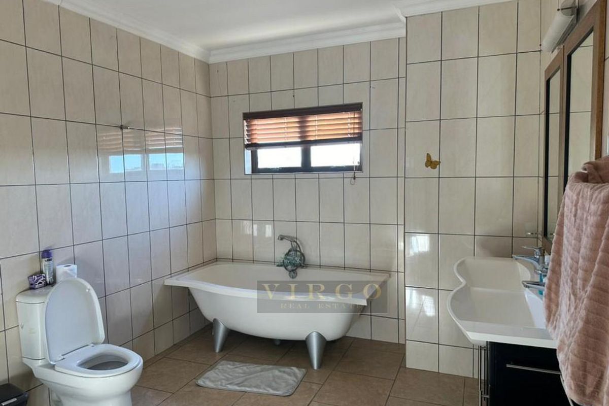 A functional bathroom featuring a freestanding bathtub, wall-mounted basin, and toilet, finished with neutral wall and floor tiles.