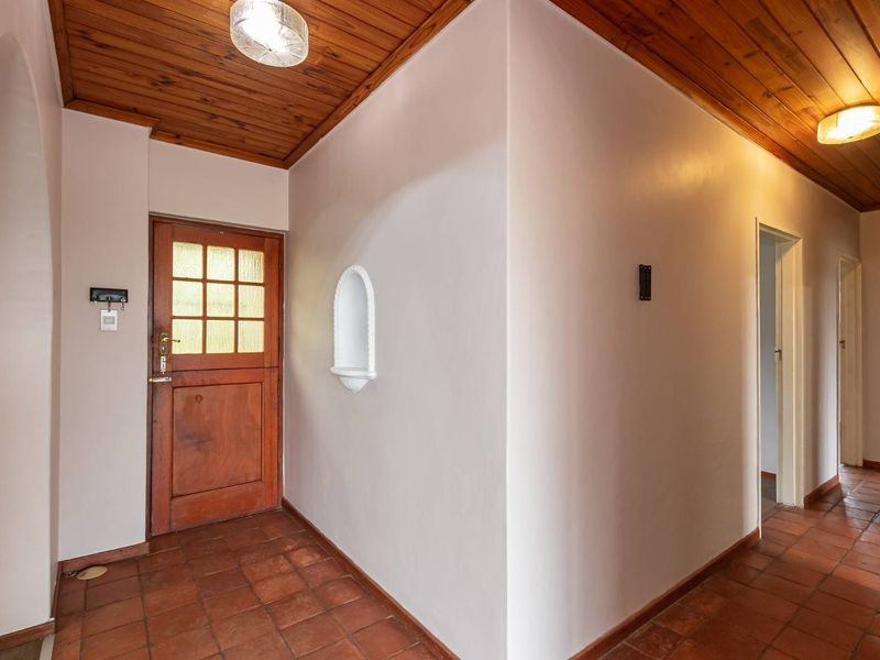 Entrance hall featuring terracotta floor tiles, a timber ceiling, and a decorative arched wall niche, providing a warm and welcoming transition into the home.