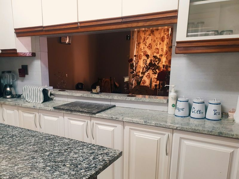 A functional kitchen featuring white cabinetry, granite countertops, and a convenient pass-through window connecting to the adjacent living or dining area.