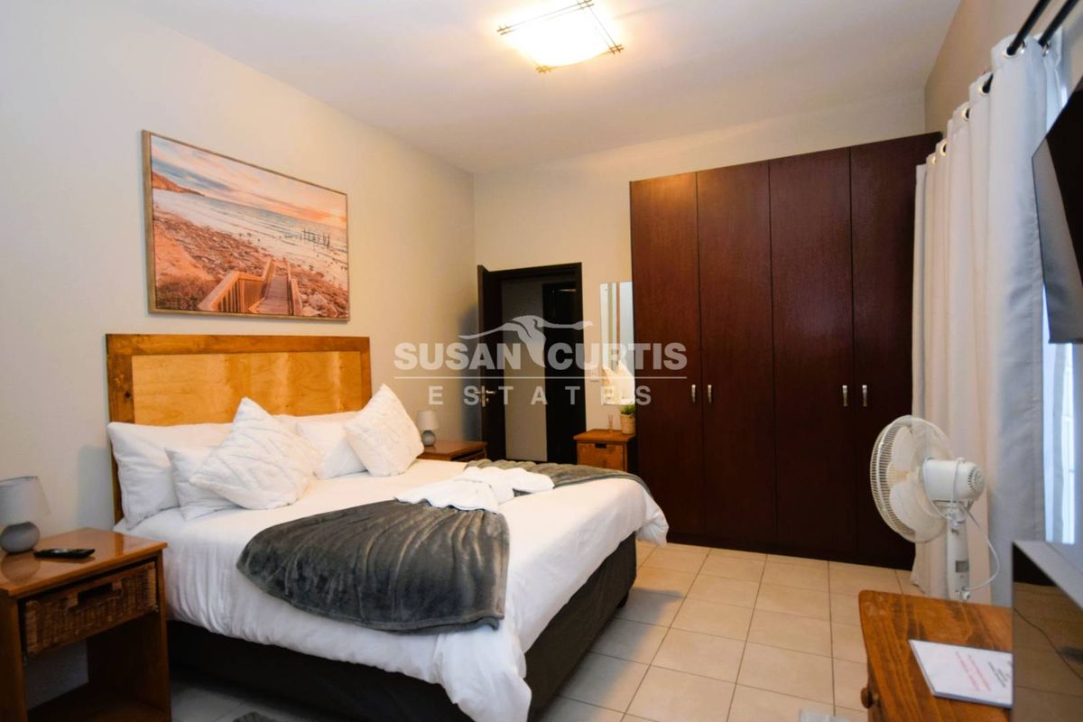 A well-maintained bedroom featuring built-in dark wood cabinetry, tiled flooring, and a central ceiling light fixture.