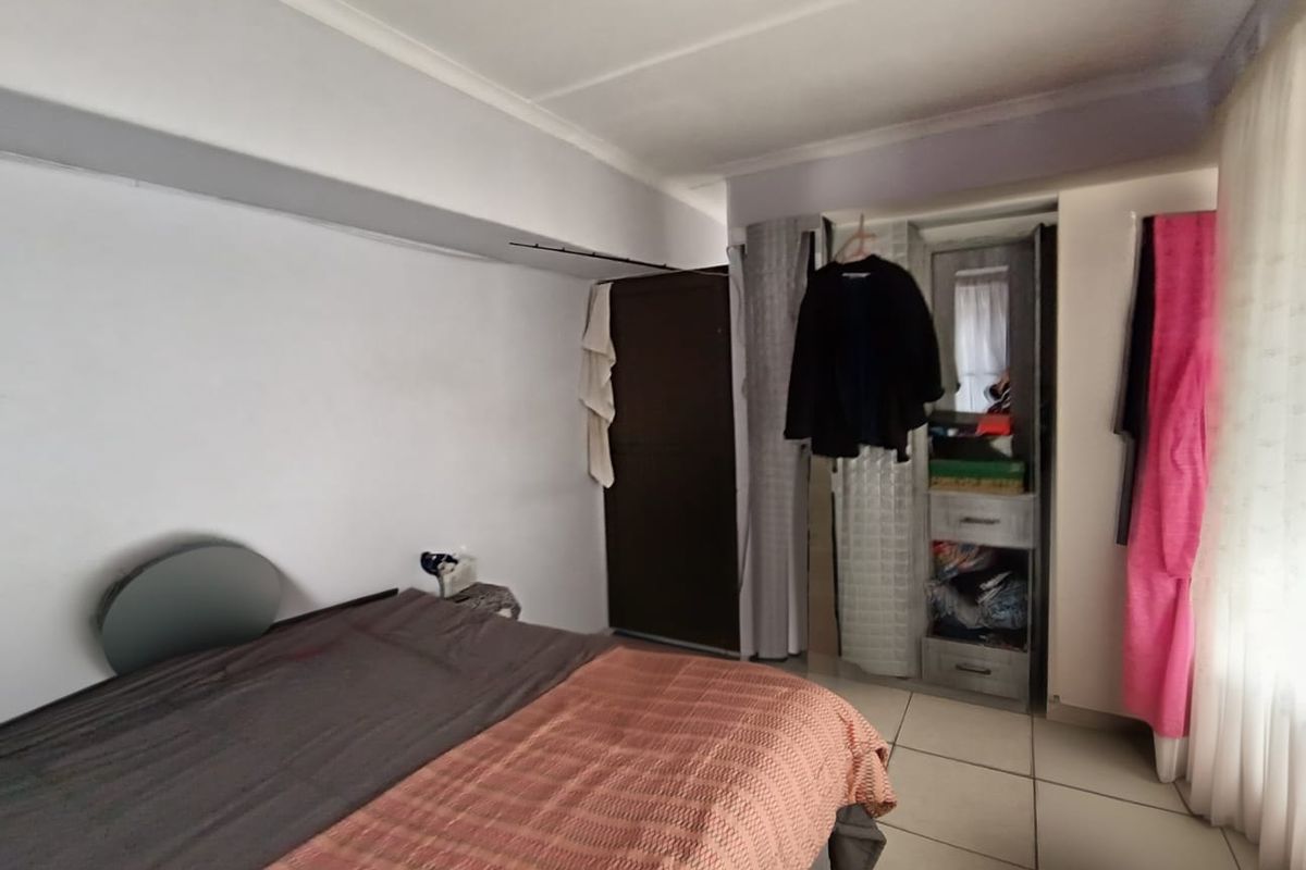 A bedroom featuring tiled flooring and a built-in cupboard, offering a functional space with neutral wall finishes.