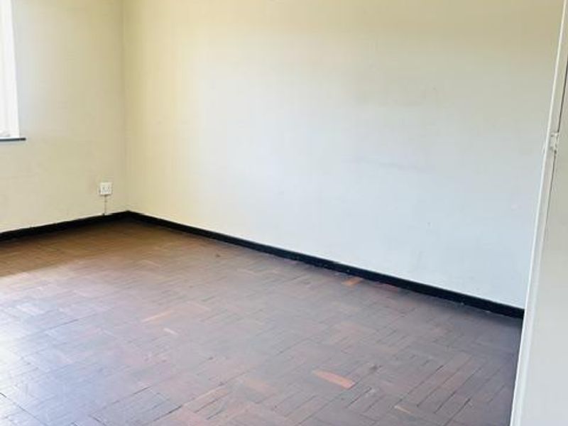 An empty bedroom featuring original parquet flooring and neutral walls, offering a blank canvas for renovation or interior design updates.
