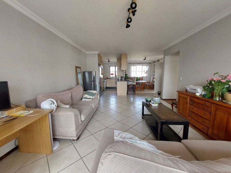 Spacious open-plan living and kitchen area featuring neutral wall tones, tiled flooring, and a functional kitchen layout with a central island.