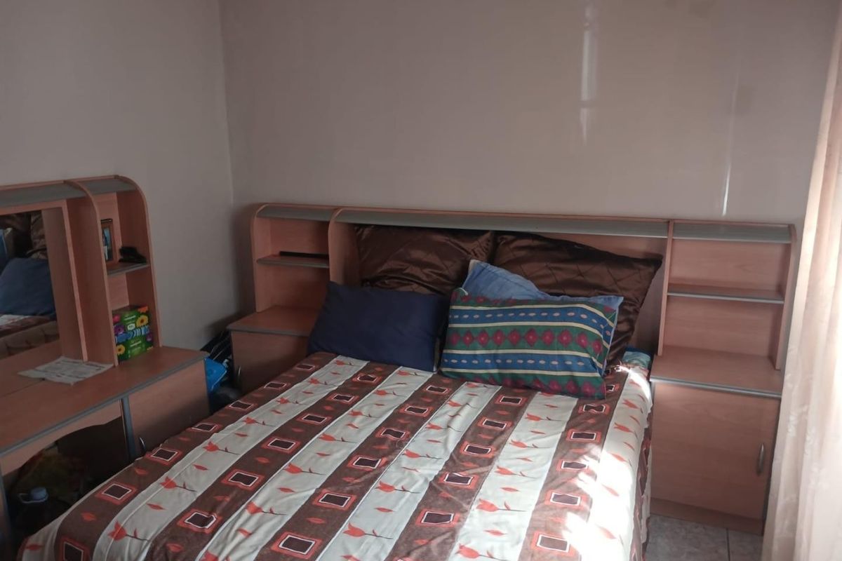 A bedroom featuring a built-in headboard with integrated bedside shelving and tiled flooring.