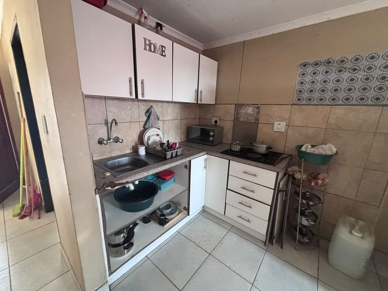 Compact kitchen featuring built-in cabinetry, tiled backsplash, and a built-in hob, requiring some maintenance and cosmetic updates to improve functionality and aesthetic appeal.