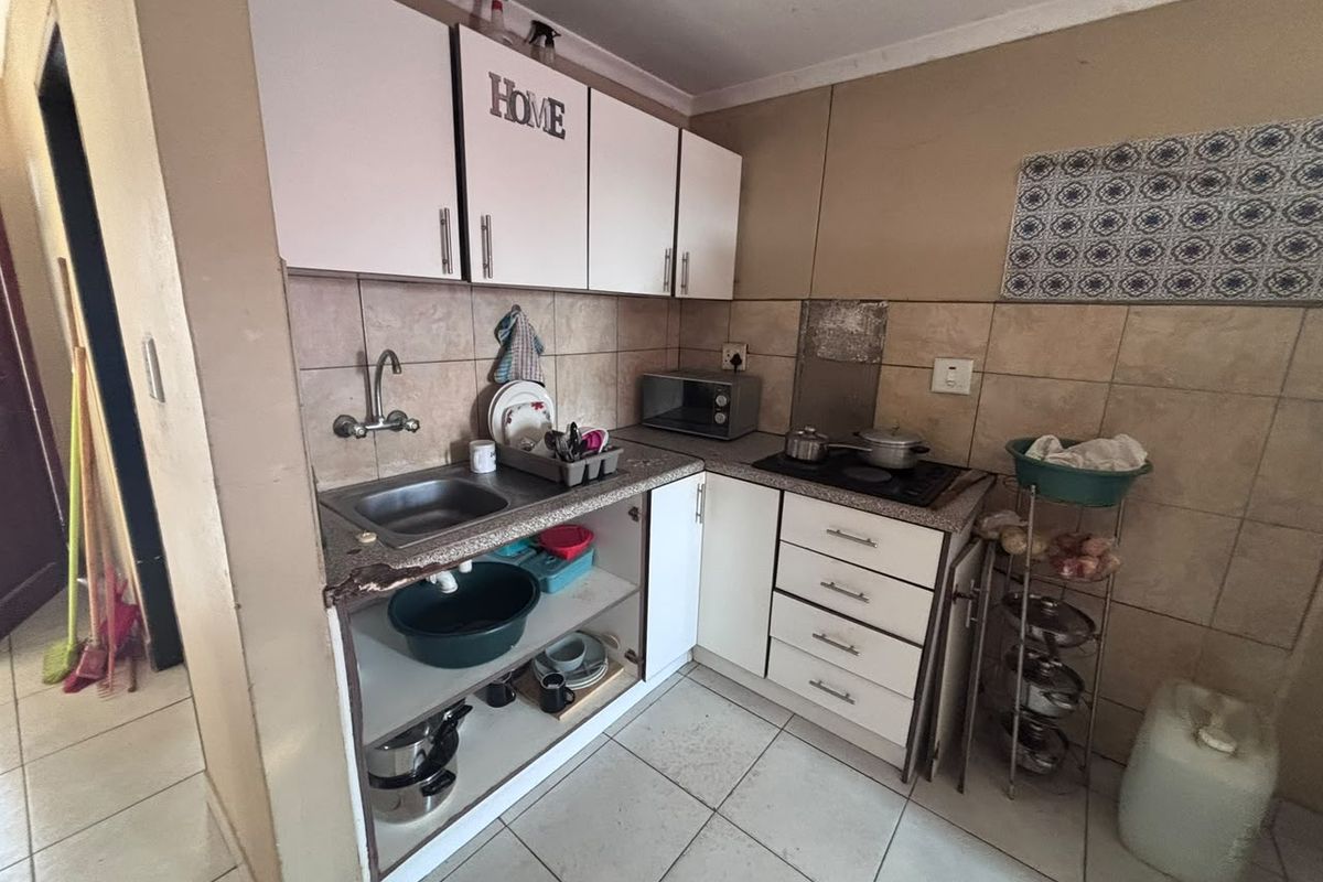 Compact kitchen featuring built-in cabinetry, tiled backsplash, and a built-in hob, requiring some maintenance and cosmetic updates to improve functionality and aesthetic appeal.