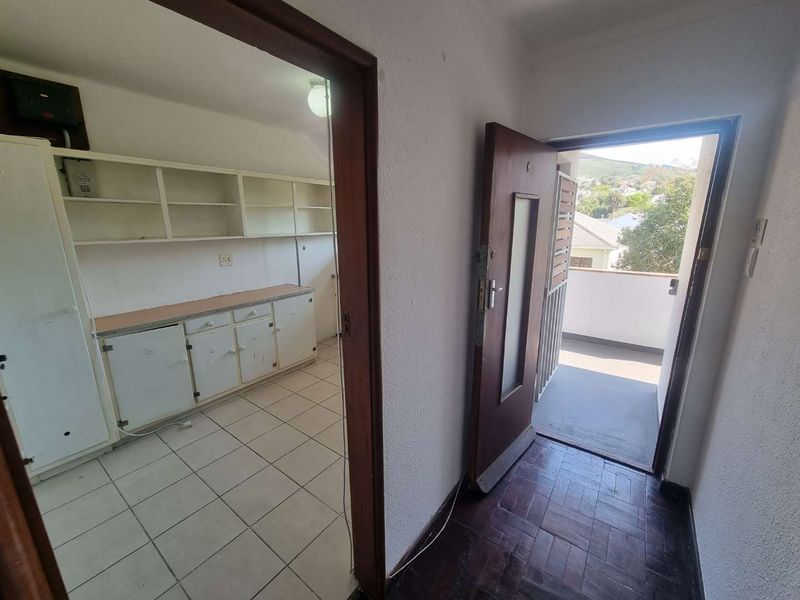 Entrance area featuring parquet flooring and a doorway leading to a utility space with built-in cabinetry and tiled floors.