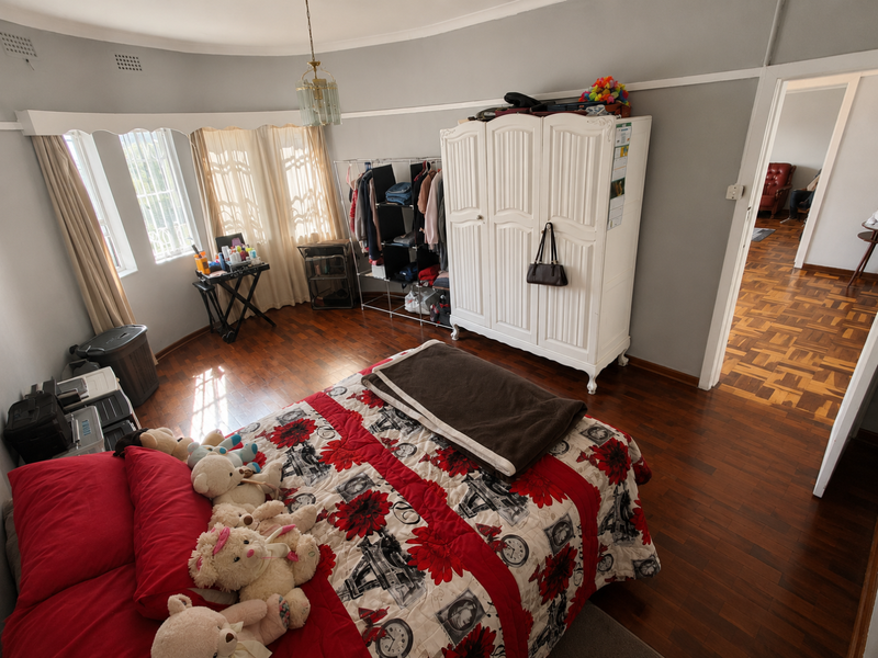 Spacious bedroom featuring classic parquet flooring, coved ceilings, and a large built-in wardrobe, offering a comfortable and well-lit living space.