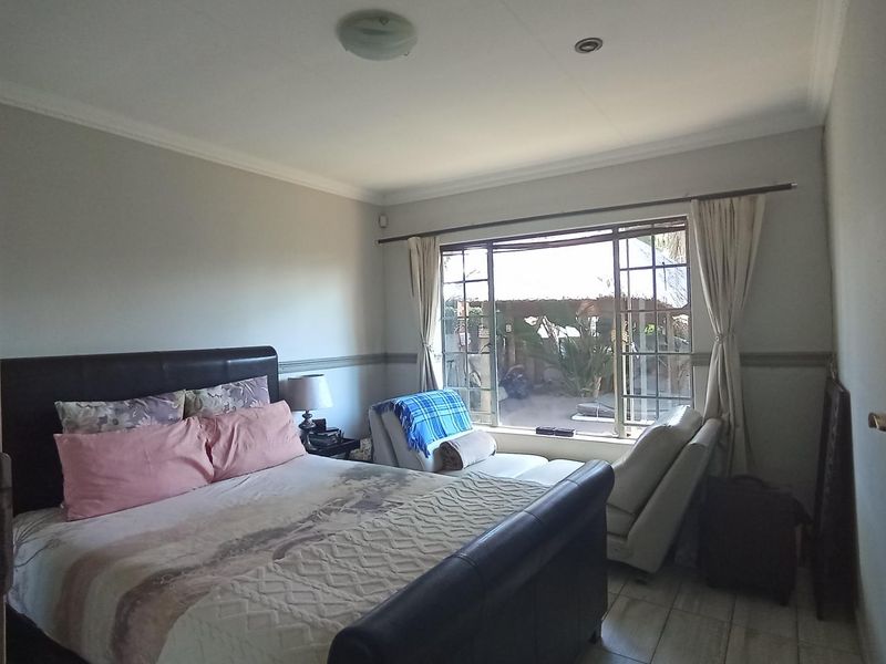 A bedroom featuring tiled flooring, a large window providing natural light, and neutral wall finishes.