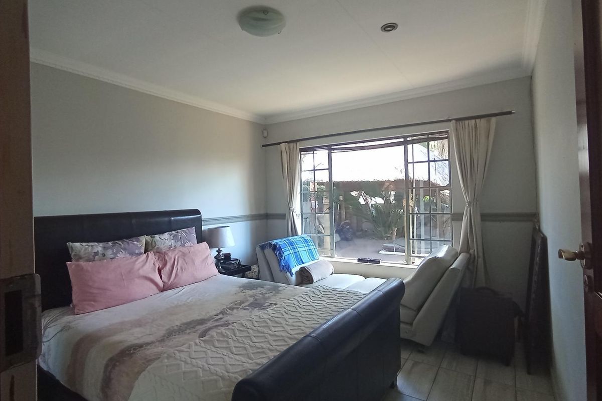 A bedroom featuring tiled flooring, a large window providing natural light, and neutral wall finishes.