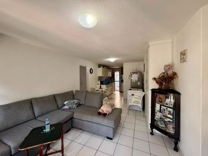 Open plan living and kitchen area featuring tiled flooring and functional built-in cabinetry, providing a versatile space for daily living.