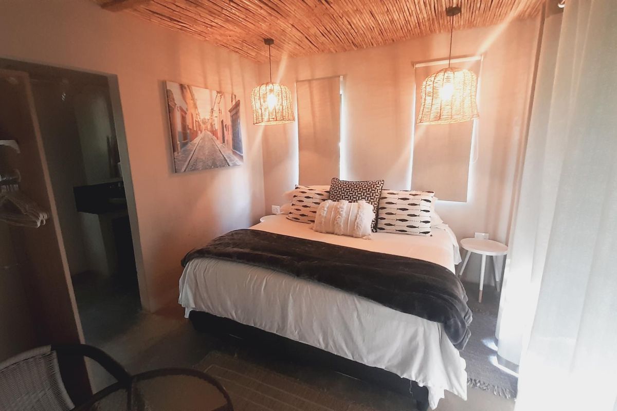 A cozy bedroom featuring a unique thatched ceiling, built-in wardrobe, and warm ambient lighting, creating a comfortable and inviting atmosphere.