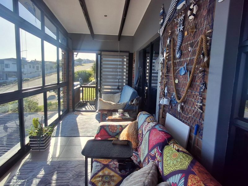 An enclosed sunroom or patio featuring large glass windows, exposed brick walls, and tiled flooring, offering a bright and versatile living space.
