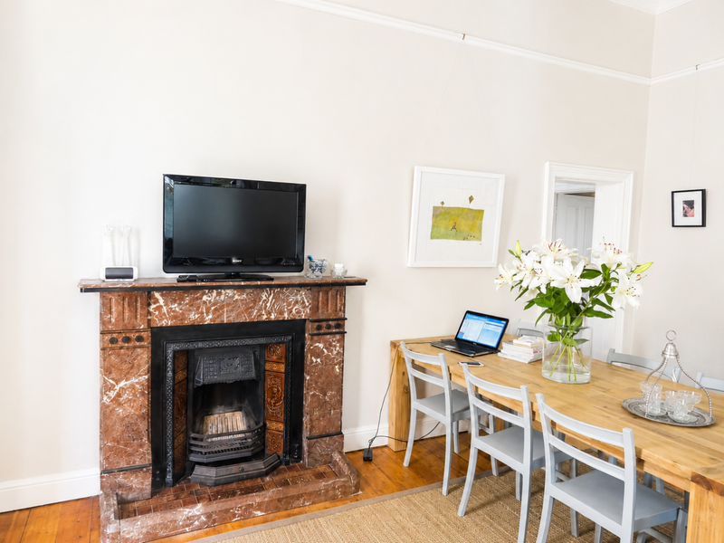 A well-maintained living area featuring a classic marble fireplace with a cast iron insert, complemented by original timber flooring and traditional picture rails.