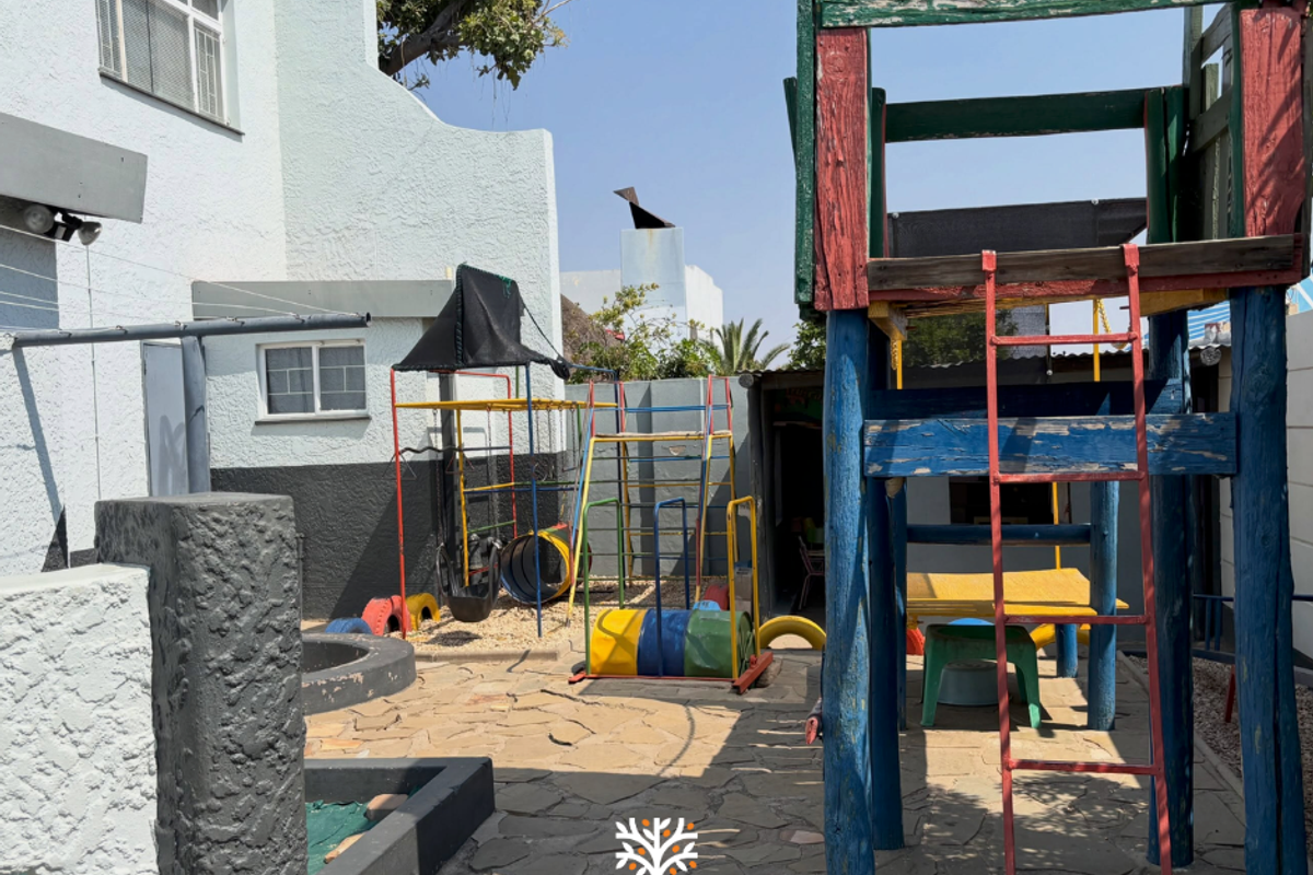Rear outdoor area featuring stone paving and a built-in sandpit, currently utilized as a play space with various fixed play structures.