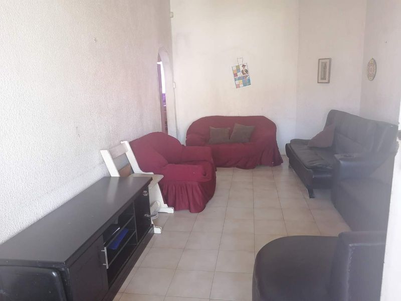 A living room featuring tiled flooring and an arched doorway, currently requiring cosmetic updates to the wall finishes to improve the overall aesthetic.