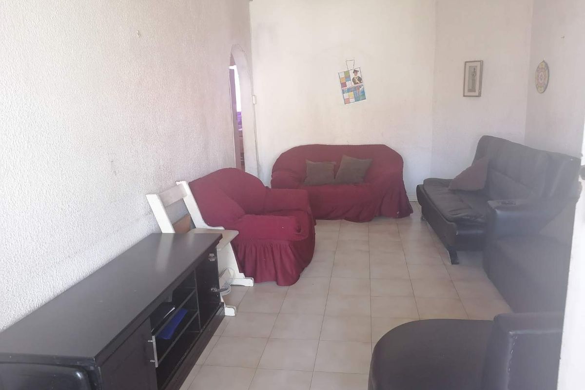 A living room featuring tiled flooring and an arched doorway, currently requiring cosmetic updates to the wall finishes to improve the overall aesthetic.