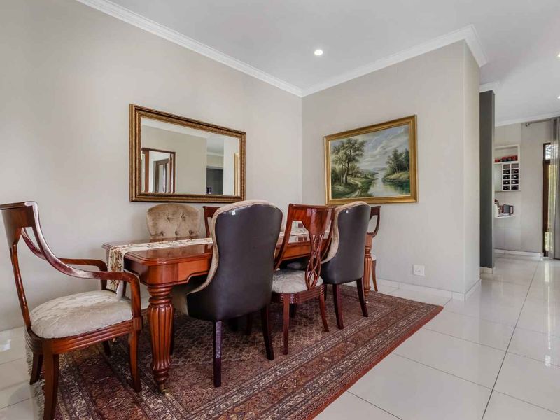 A well-maintained dining room featuring neutral walls, recessed downlighting, and polished porcelain floor tiles, creating a bright and inviting space for formal meals.