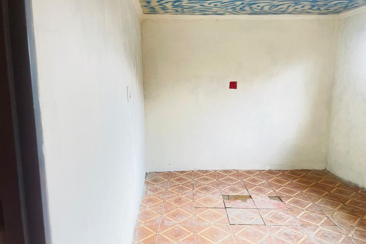 An empty, unfinished room featuring tiled flooring with visible damage and a decorative painted ceiling.