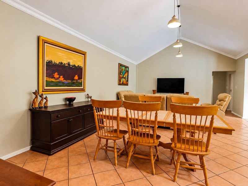 Spacious open-plan living and dining area featuring vaulted ceilings, ceramic tile flooring, and elegant pendant lighting, creating a bright and inviting atmosphere.