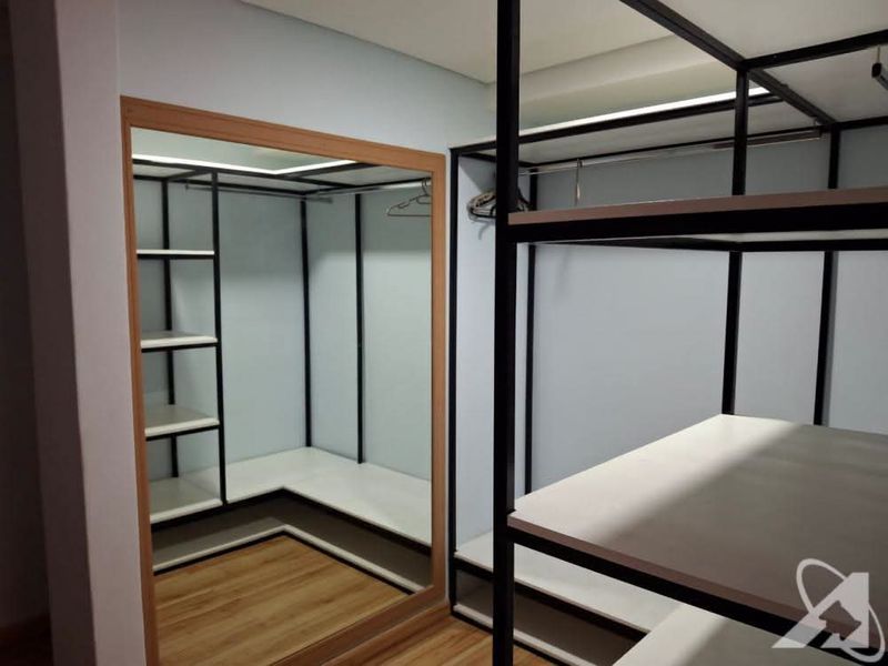 A modern walk-in closet area featuring custom black metal shelving, integrated clothing rails, and a large framed mirror with laminate flooring.