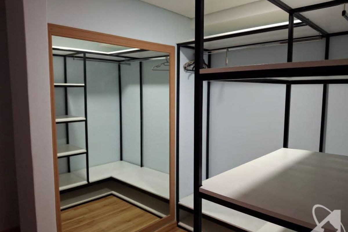A modern walk-in closet area featuring custom black metal shelving, integrated clothing rails, and a large framed mirror with laminate flooring.