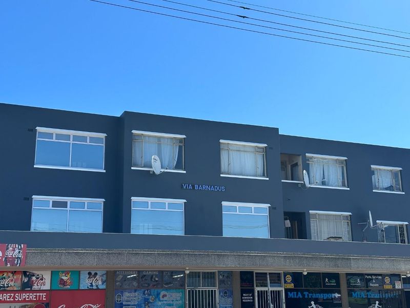 Front elevation of a multi-story retail and residential building featuring ground-floor commercial storefronts and upper-level residential units with aluminium windows.