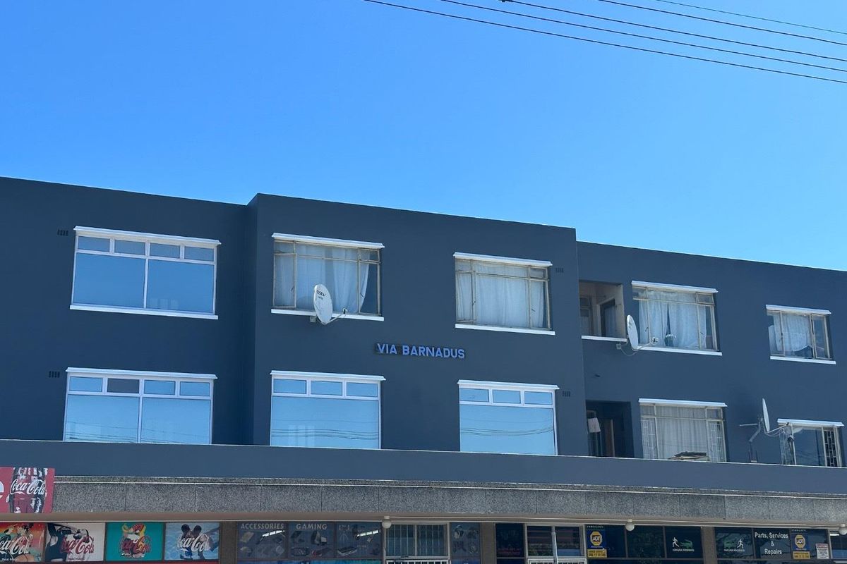 Front elevation of a multi-story retail and residential building featuring ground-floor commercial storefronts and upper-level residential units with aluminium windows.