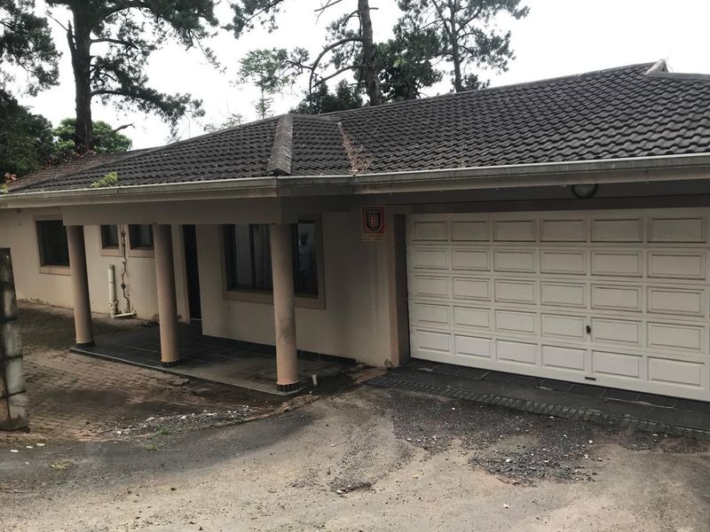 Front exterior view of the townhouse featuring a tiled roof, covered porch with concrete columns, and an integrated garage with a paved driveway.
