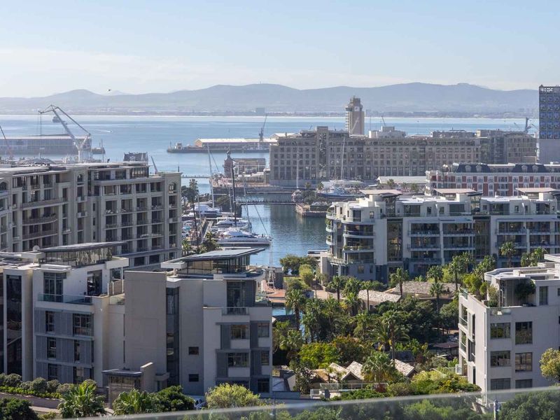 Elevated panoramic view overlooking the marina, harbour, and surrounding urban landscape with distant mountain scenery.