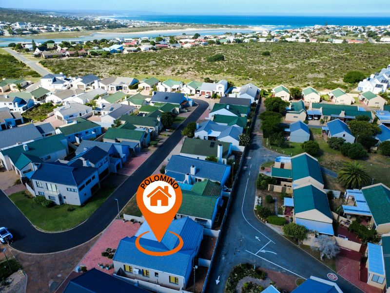 Aerial view of a residential property within a coastal estate, showcasing the roof structure, driveway, and surrounding neighborhood proximity to the ocean.