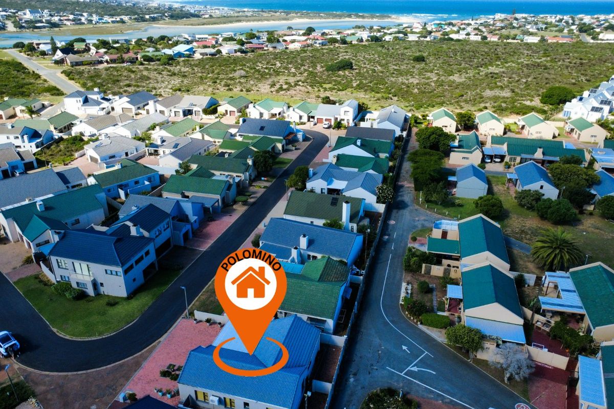 Aerial view of a residential property within a coastal estate, showcasing the roof structure, driveway, and surrounding neighborhood proximity to the ocean.