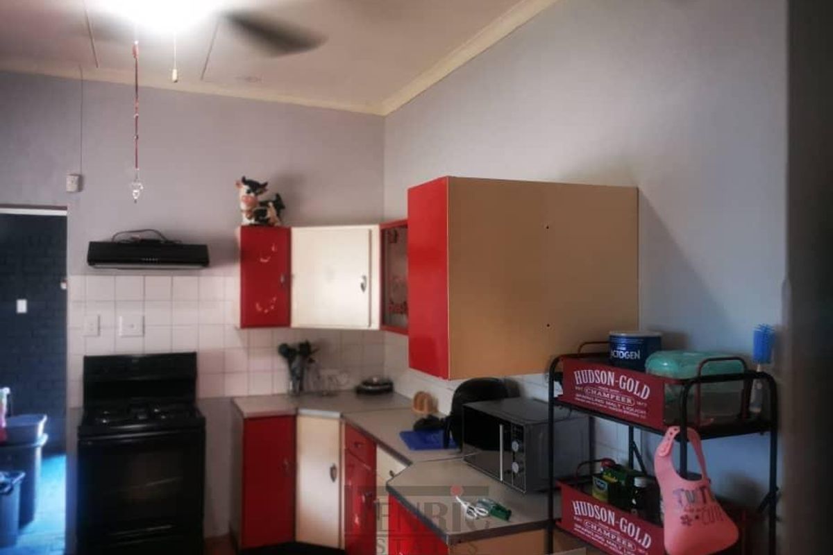 A functional kitchen featuring red and cream cabinetry, a built-in stove with extractor fan, and tiled splashbacks.