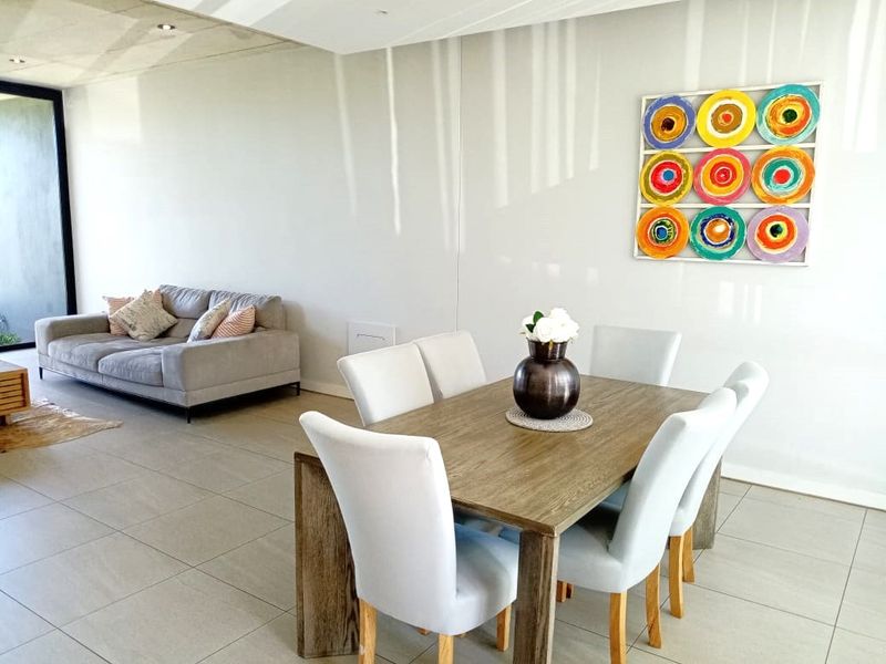 Spacious open-plan living and dining area featuring neutral tiled flooring, recessed ceiling lighting, and large sliding glass doors leading to an outdoor space.