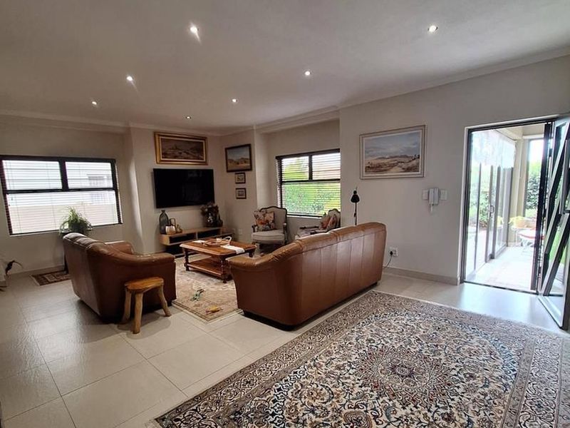 Spacious living room featuring neutral tiled flooring, recessed downlighting, and large sliding glass doors providing direct access to the outdoor patio area.