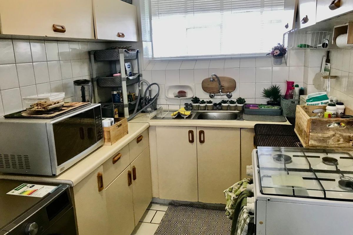 A compact kitchen featuring laminate countertops, tiled backsplash, built-in cabinetry, and a gas stove, offering a functional layout with potential for modernization.