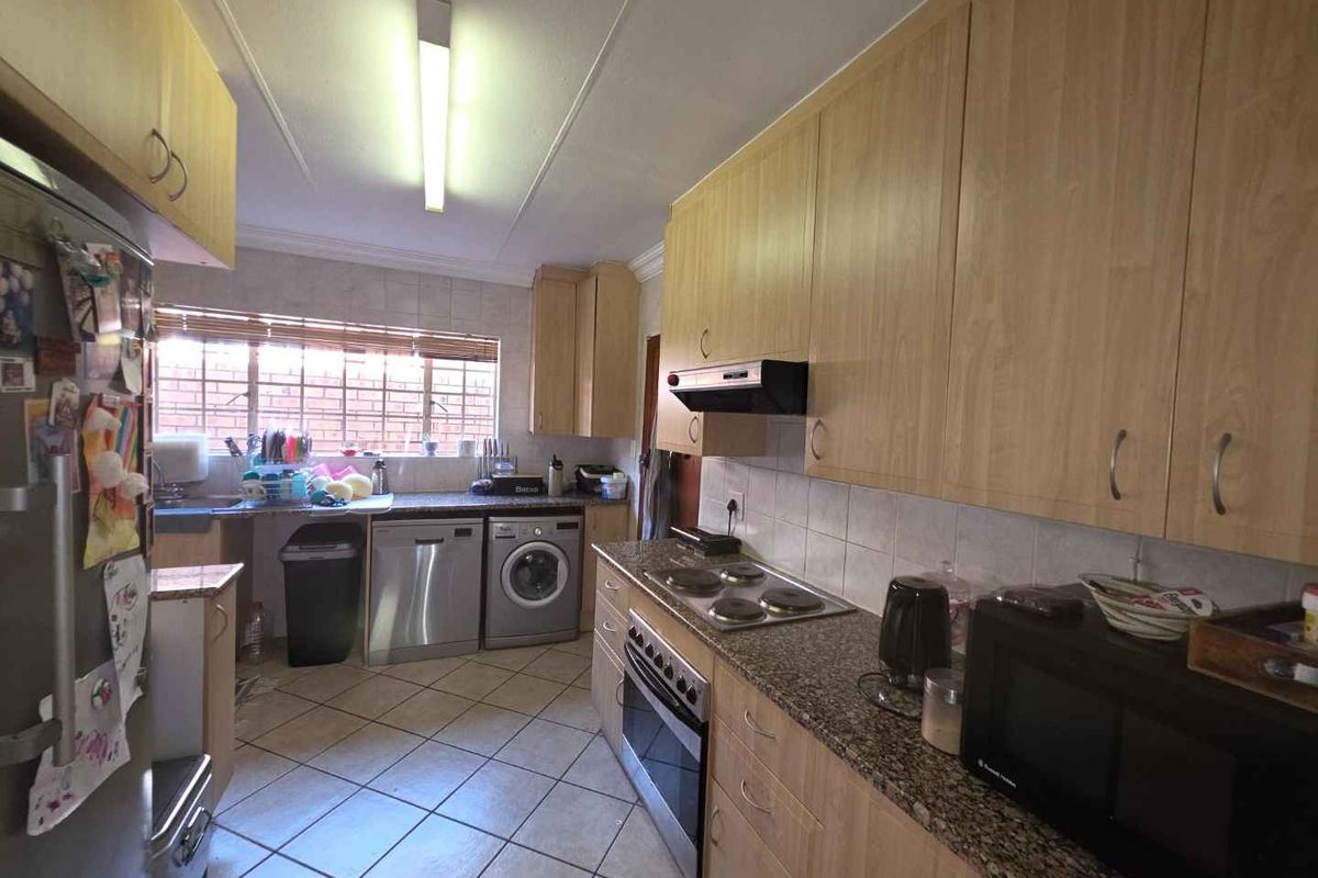 Functional kitchen featuring laminate cabinetry, granite countertops, built-in oven, electric hob, and tiled flooring with integrated laundry appliance space.