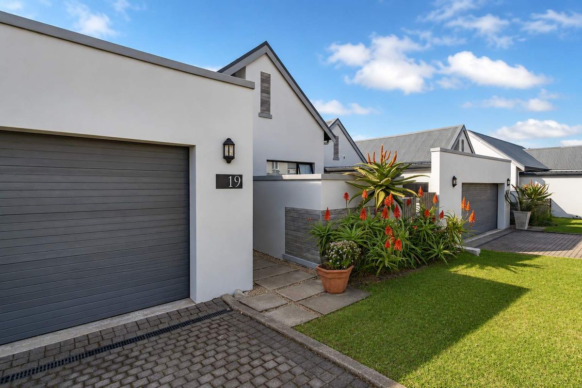 Modern exterior front view of the property featuring a paved driveway, single garage, and well-maintained landscaped garden area.