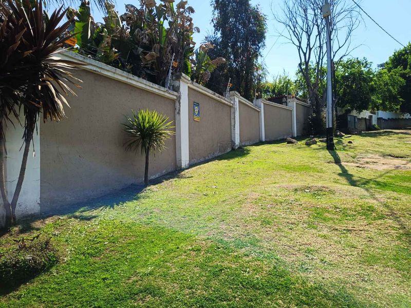 A view of the property's perimeter wall featuring integrated electric fencing and an adjacent grassed area.