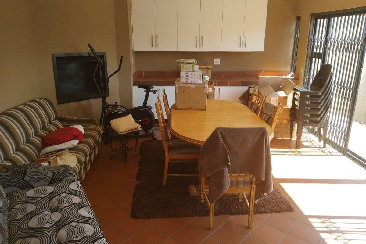 A living area featuring built-in cabinetry, a fireplace, and tiled flooring, with direct access to an outdoor space through a security gate.